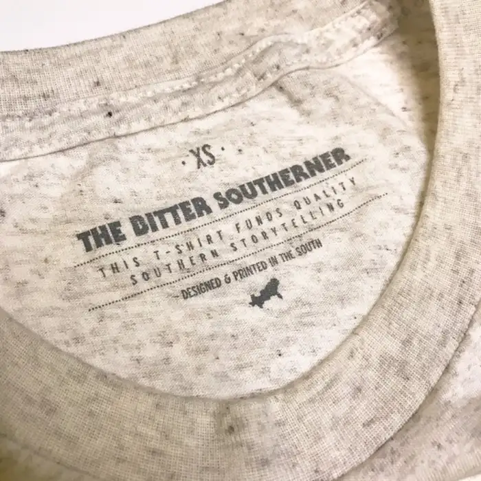 The Bitter Southerner printed neck tag in Pantone 430 C gray on an oatmeal heather shirt, size XS